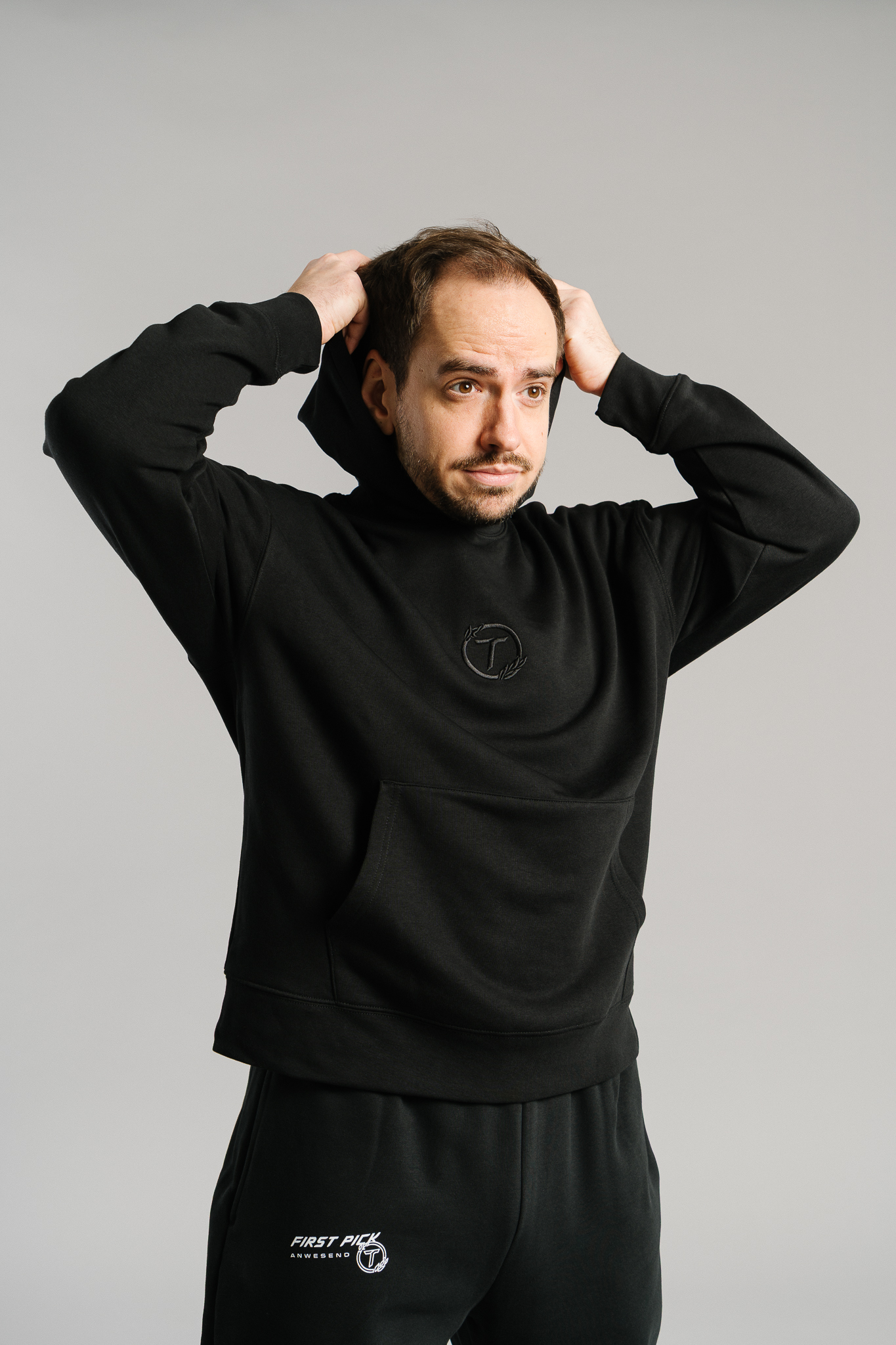 Schwarzer Hoodie aus weichem Stoff mit dezentem Ton-in-Ton-Sticklogo auf der Brust. Der Kapuzenpullover besitzt eine große Kängurutasche und eine legere Passform. Das schlichte Design wirkt sportlich und modern.