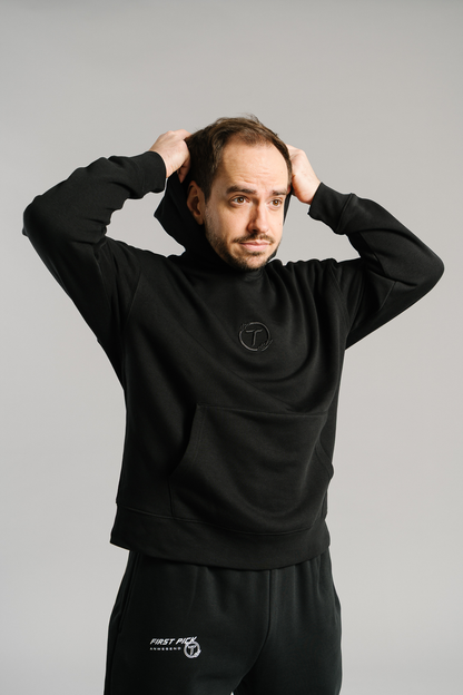 Schwarzer Hoodie aus weichem Stoff mit dezentem Ton-in-Ton-Sticklogo auf der Brust. Der Kapuzenpullover besitzt eine große Kängurutasche und eine legere Passform. Das schlichte Design wirkt sportlich und modern.