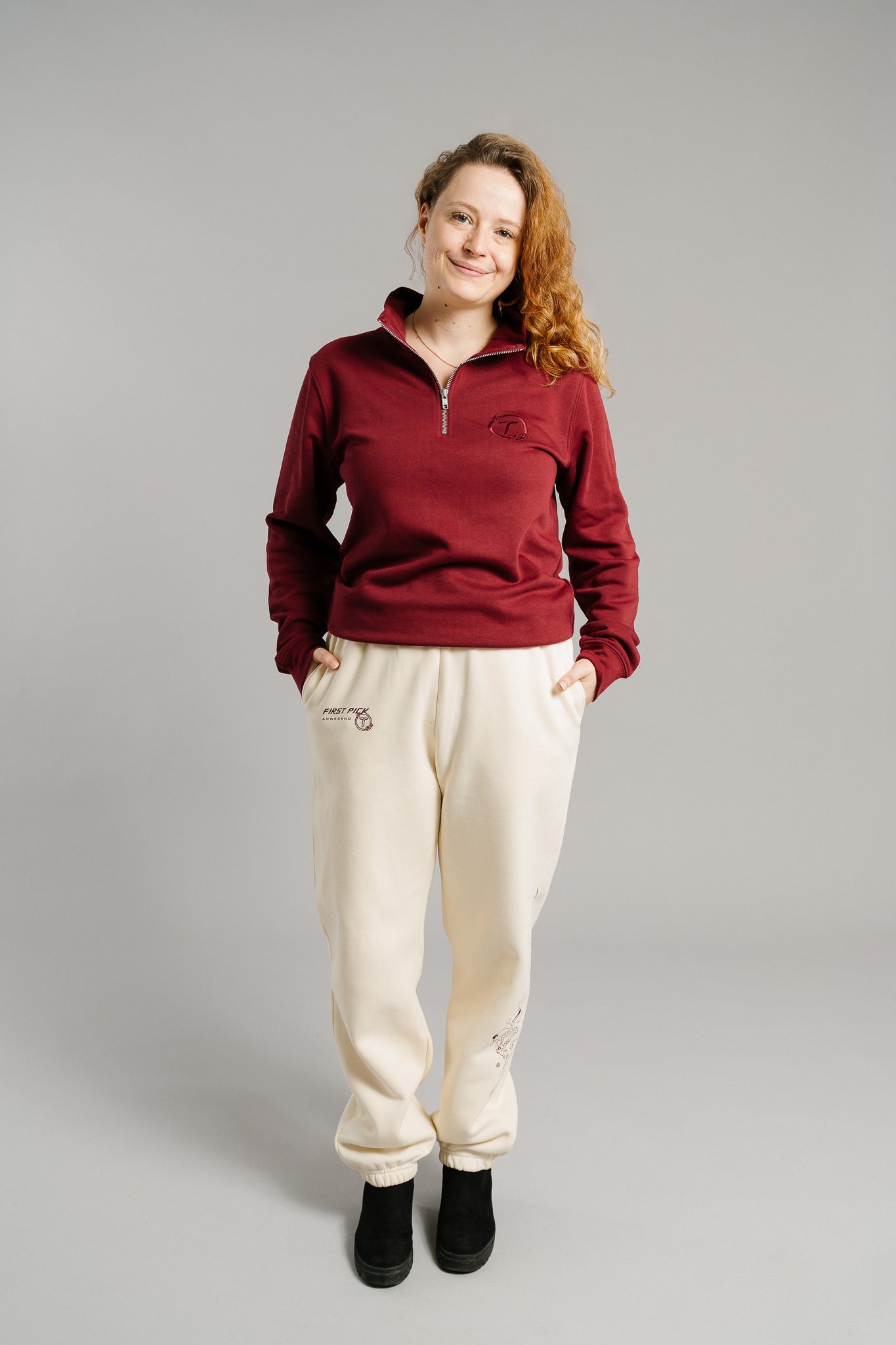 Beigefarbene Jogginghose mit lockerer Passform und elastischen Bündchen an den Knöcheln. Auf der Außenseite des rechten Beins ist ein feines, lineares Motiv in hellbrauner Farbe zu sehen. Die Hose besteht aus weichem, dickem Sweatstoff und verfügt über seitliche Eingrifftaschen.