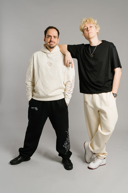 Schwarzes T-Shirt mit gesticktem Ton-in-Ton-Logo auf der Brust. Das Logo zeigt ein stilisiertes „T“ innerhalb eines Kreises mit Lorbeerzweigen. Das Shirt hat einen lockeren, geraden Schnitt aus weicher Baumwolle und verkörpert einen schlichten, modernen Streetwear-Look mit minimalistischem Design.