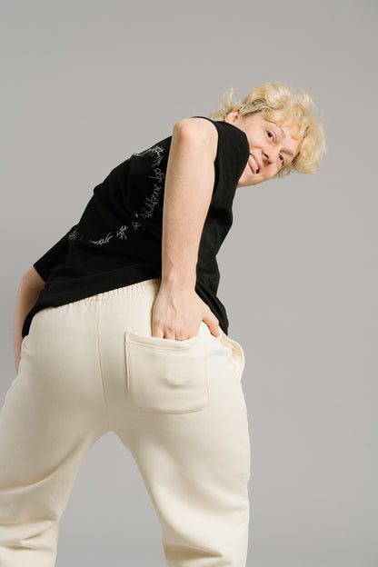 Beigefarbene Jogginghose aus weichem Sweatstoff mit aufgesetzter Gesäßtasche auf der rechten Seite. Die Hose hat eine lockere Passform und elastischen Bund, sichtbar von hinten in einer humorvollen Pose präsentiert.