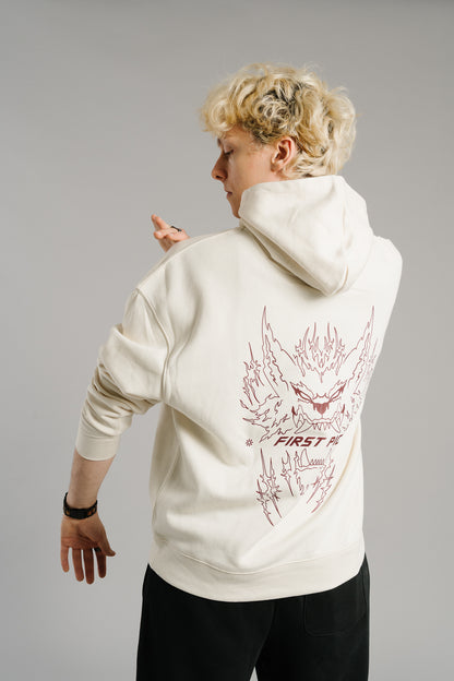 Beigefarbener Hoodie aus Sweatstoff mit großflächigem Rückendruck in Dunkelrot. Das Motiv zeigt ein stilisiertes, flammenartiges Monster-Gesicht mit spitzen Zähnen und dem Schriftzug „FIRST PICK“ darunter. Der Hoodie hat eine Kapuze und lange Ärmel mit Bündchen.